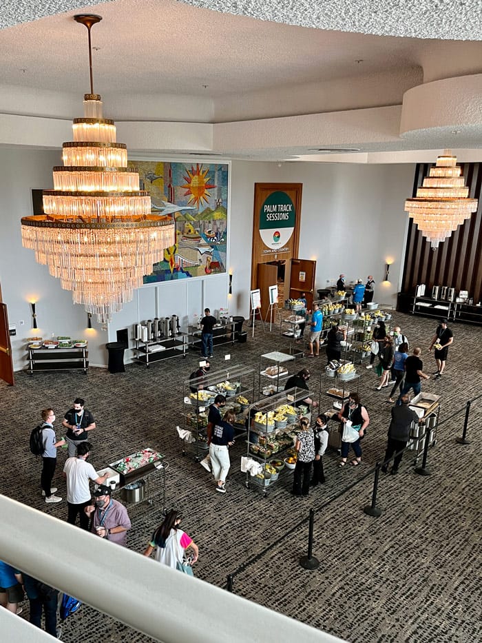 A view looking down on attendees at WordCamp getting snacks and chatting in the hotel lobby